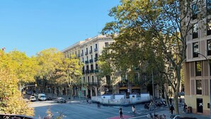 A street view with a red bus lane, parked scooters, and a building with balconies. - Hip Karma Hostel (Barcelona)