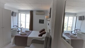 A hotel room with a large bed, two bedside tables, a TV, and a window with curtains. - Hermes (Tossa de Mar)