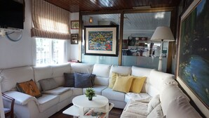 A living room with a white sofa, a small white table with a plant, and a painting on the wall. - Hermes (Tossa de Mar)