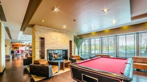 Un espace intérieur vaste et accueillant, doté d’une table de billard, de sièges confortables, d’une cheminée et de grandes fenêtres offrant une vue panoramique.