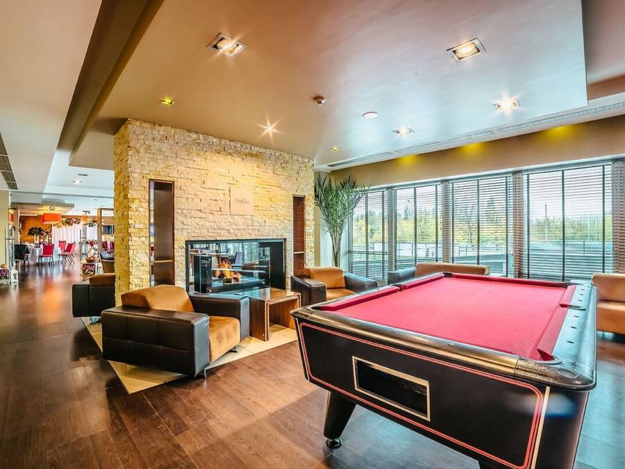 A spacious indoor area with a pool table, comfortable seating, a fireplace, and large windows offering a view.
