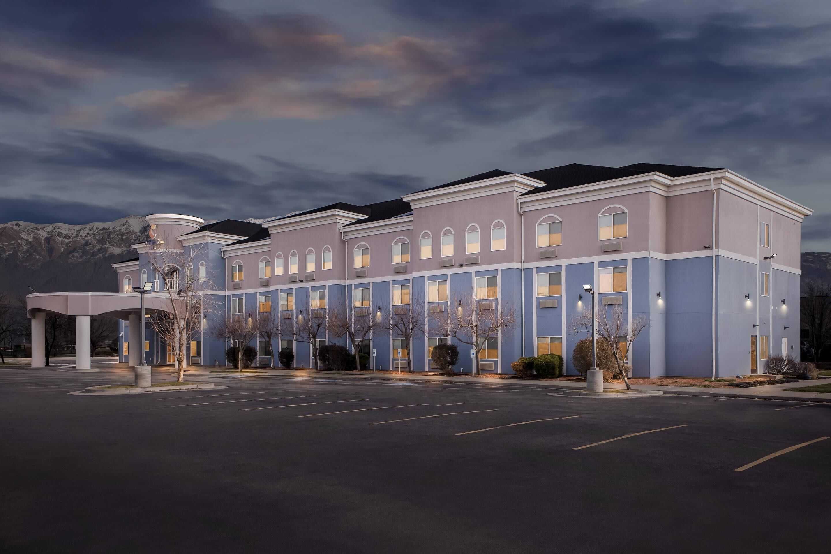 A multi-story hotel with a flat roof, large windows, and a parking lot.