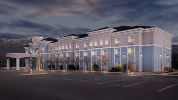 A multi-story hotel with a flat roof, large windows, and a parking lot.