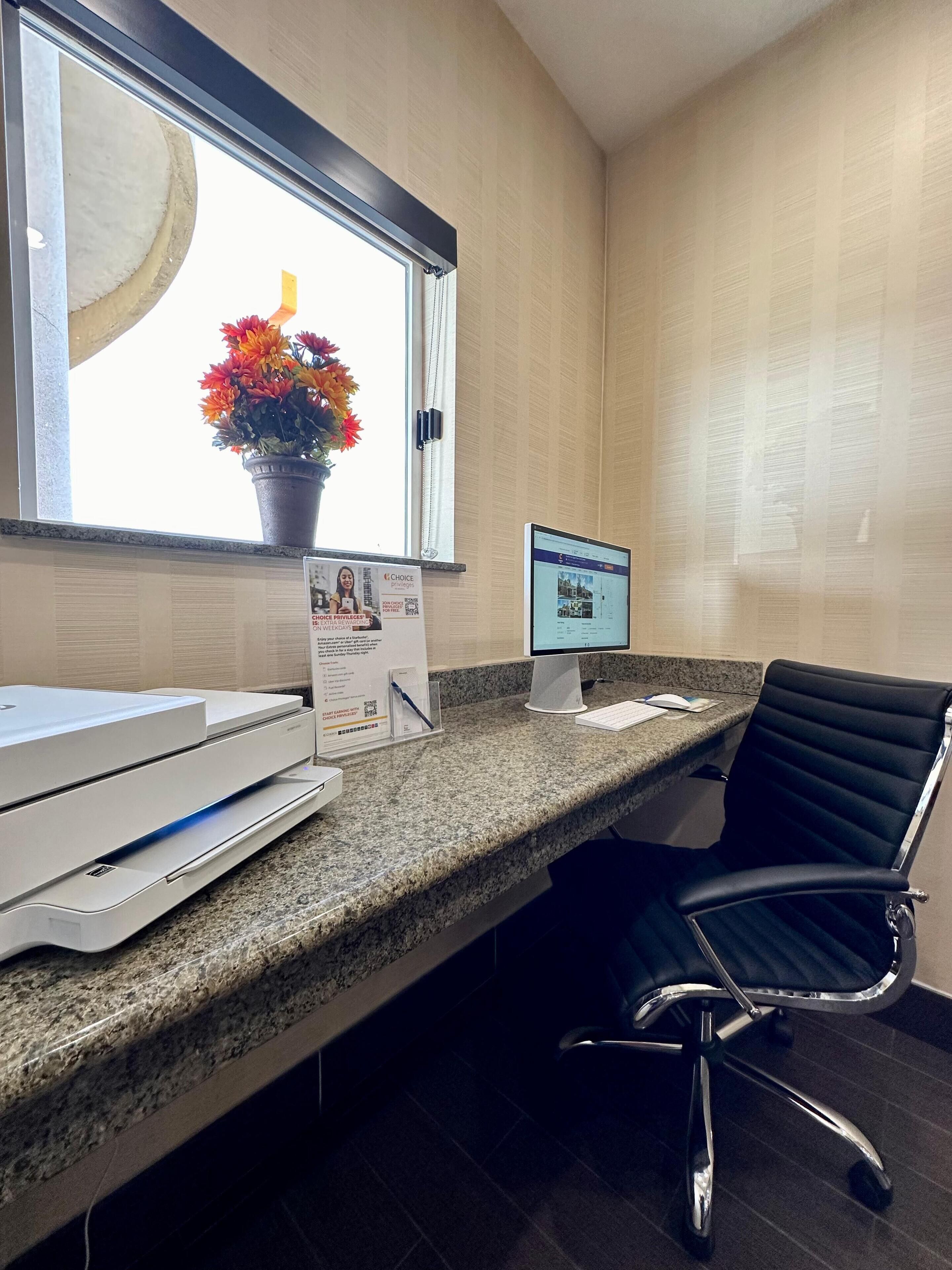 A reception desk with a computer, printer, and a chair.