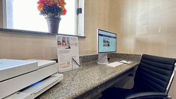 A reception desk with a computer, printer, and a chair.