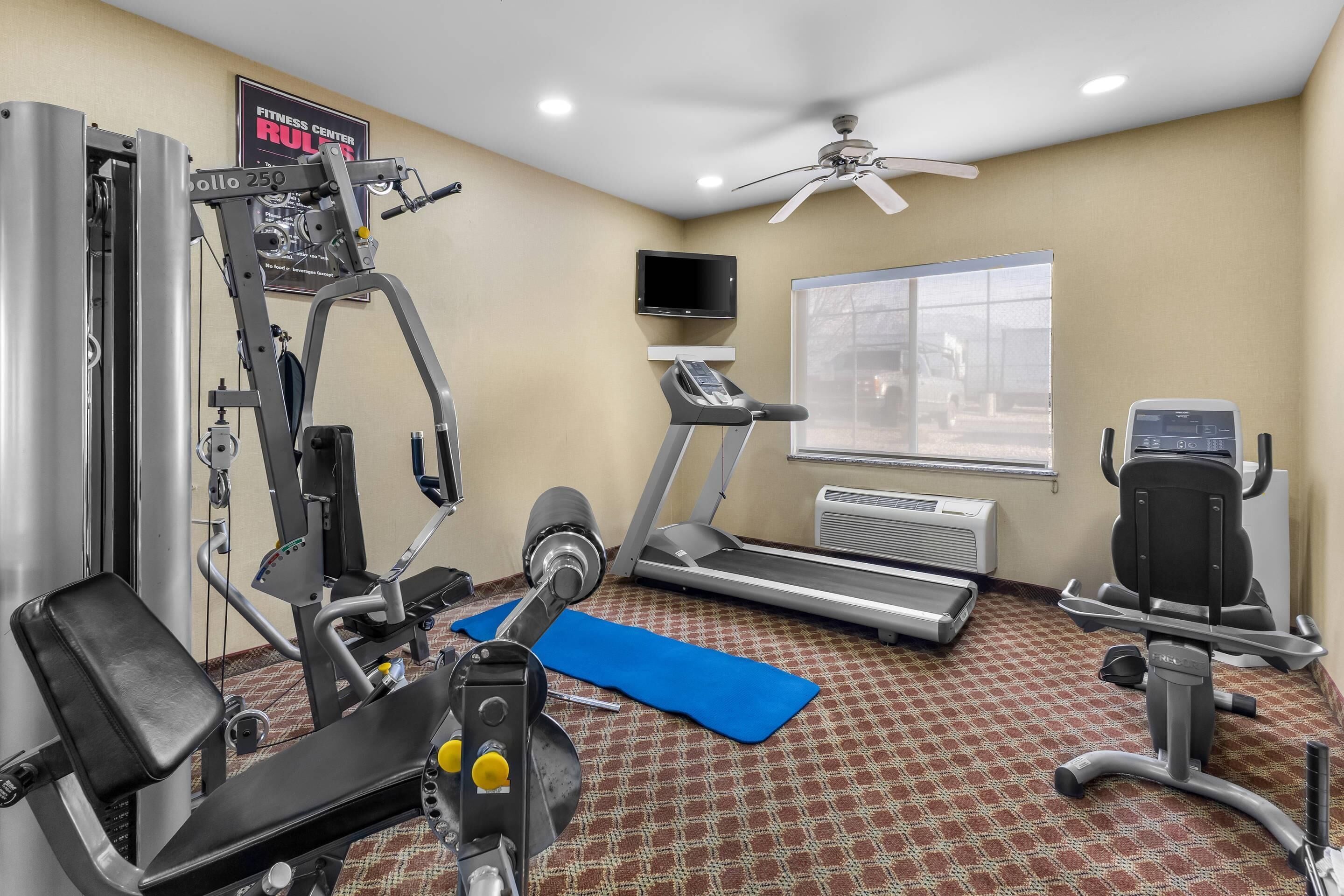 A fitness center with cardio equipment, a TV, and a ceiling fan.