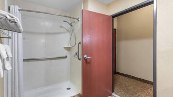 A bathroom with a shower, a towel rack, and a wooden door.