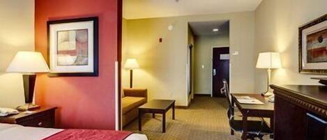 A hotel room with a bed, desk, chair, and lamps.