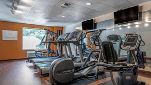 A gym with treadmills, ellipticals, and weight machines, a TV on the wall, and a motivational sign. - Comfort Suites Biloxi - Ocean Springs (Biloxi)