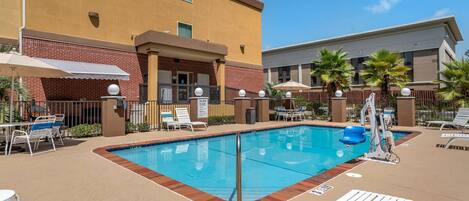 A hotel pool area with lounge chairs, a diving board, and a clear blue pool.