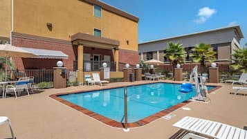Una piscina al aire libre, sombrillas, sillones reclinables de piscina