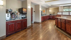 A spacious kitchen with wooden cabinets, a coffee machine, and a large island with a granite countertop. - Comfort Suites Biloxi - Ocean Springs (Biloxi)