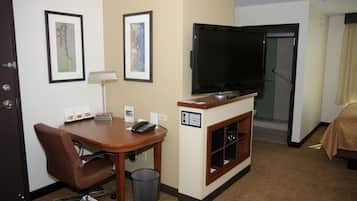 A hotel room with a desk, chair, television, and a bed.