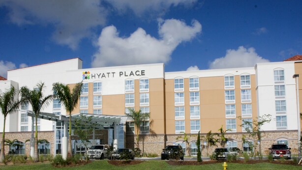 A multi-story hotel with a clear sky, palm trees, and a sign reading "HYATT PLACE". - Hyatt Place Fort Myers/at The Forum (Fort Myers)
