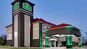 Un hotel con una torre destacada, señalización, una entrada cubierta y techo rojo.