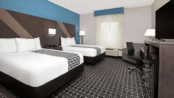 A hotel room with two beds, a desk, a chair, and a TV.
