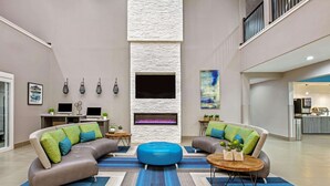 Una sala moderna con un sofá modular, un otomano azul y una chimenea.