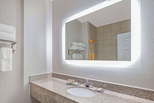Un baño con encimera de granito, un lavabo, un espejo y un perchero con toallas dobladas.