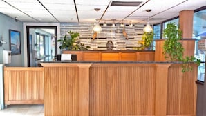 Un mostrador de recepción con detalles de madera, iluminación colgante y plantas en macetas.