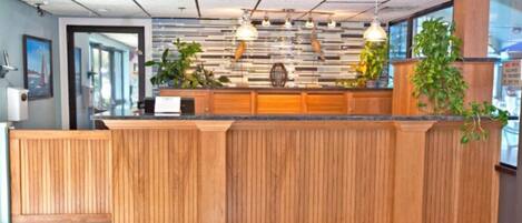 A reception desk with a wooden finish, pendant lighting, and potted plants.
