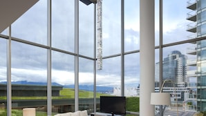 Una sala de estar moderna con un ventanal grande, un televisor de pantalla plana y un sofá.