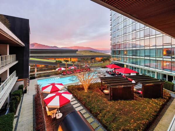 A hotel with a pool area, outdoor seating, and a view of mountains.