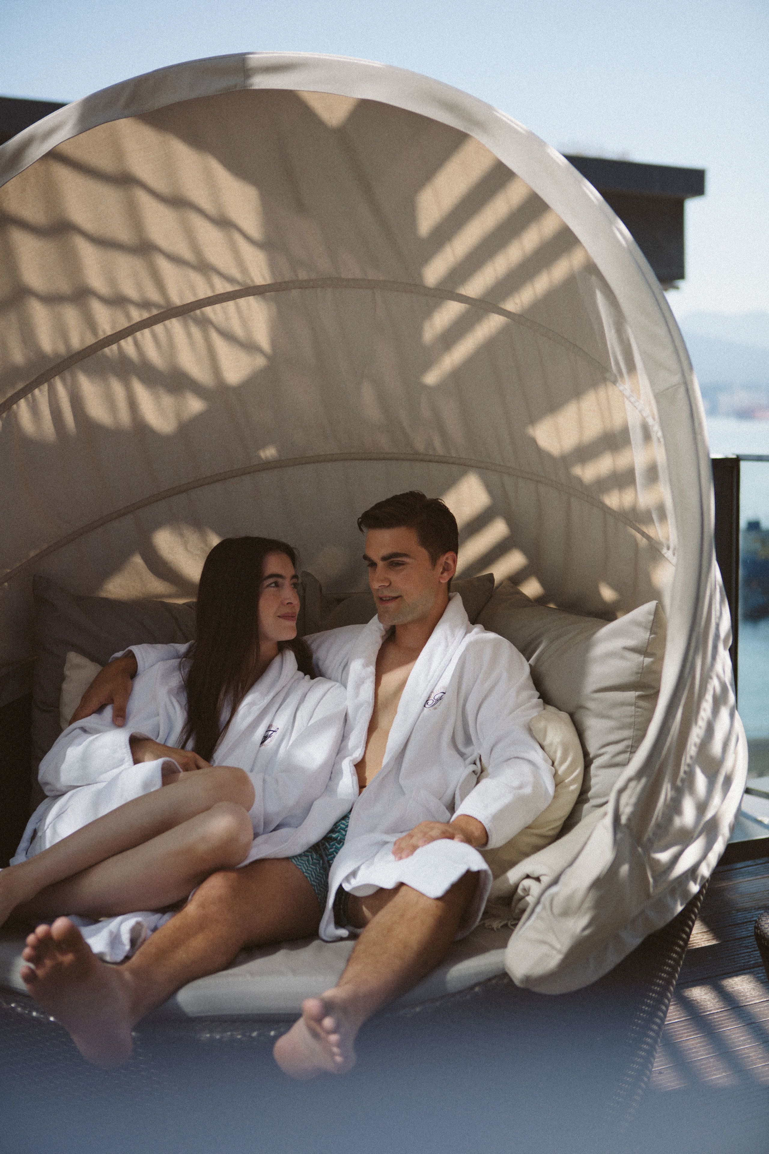 A couple in a circular, fabric-covered seating area with a view of the sky and mountains.
