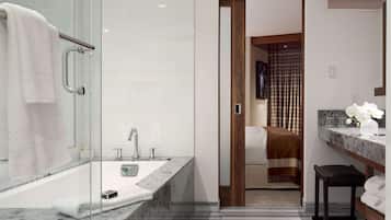 Un baño moderno con cabina de ducha de vidrio, lavamanos de mármol y tocador de madera.