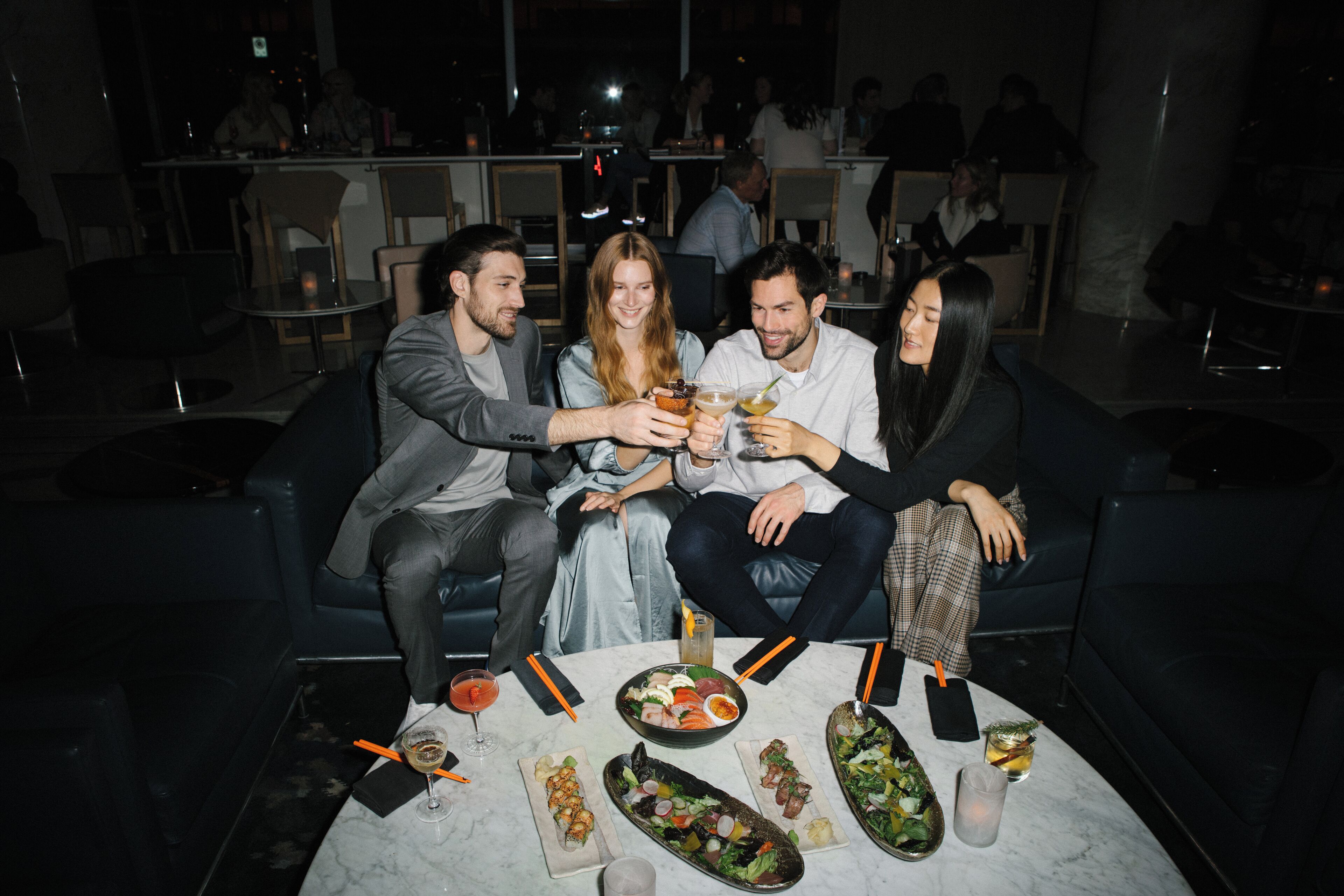 Un groupe de personnes est assis à une table, devant divers plats et boissons.