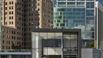 A modern building with a glass facade, a pool area, and a view of a historic building with a dome.