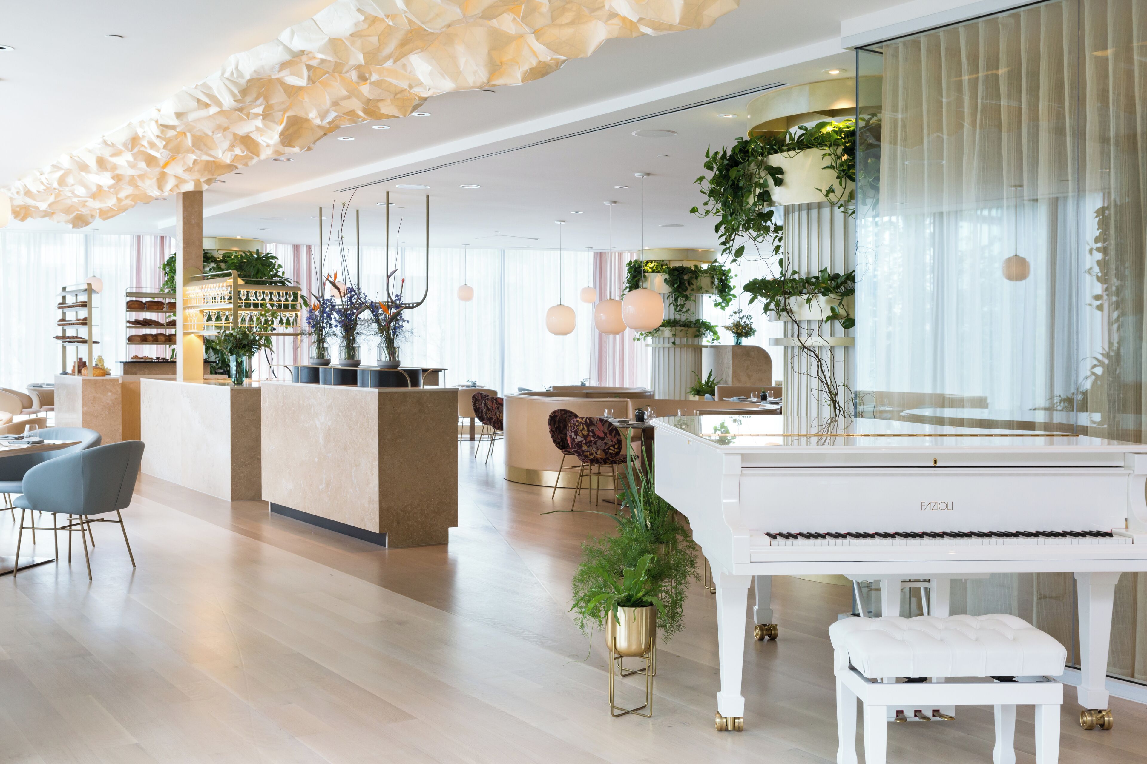 Un amplio vestíbulo de hotel con un piano de cola, una recepción y zonas de estar modernas.