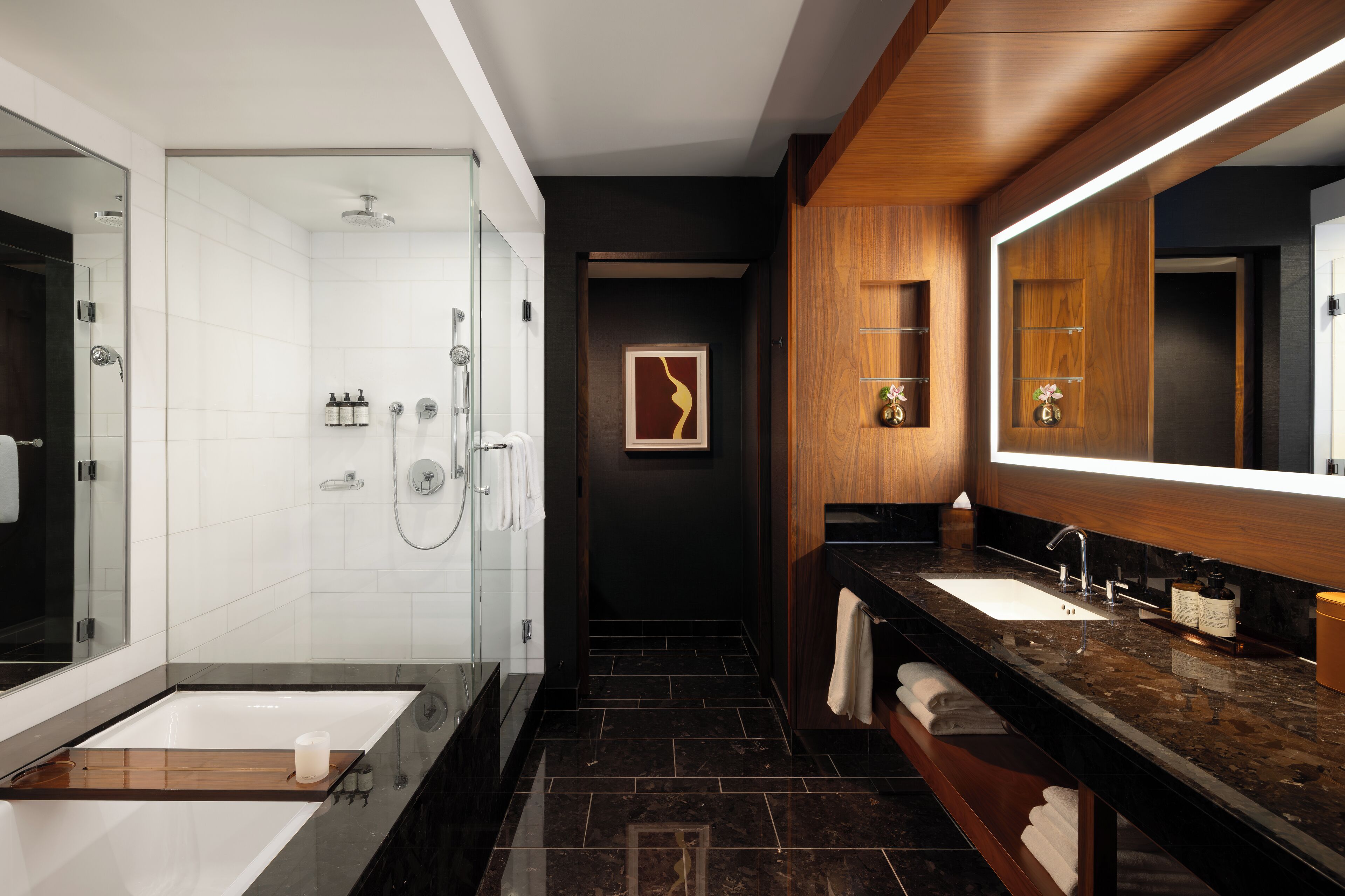 A modern bathroom with a glass-enclosed shower, a large mirror, and a dark wood vanity.