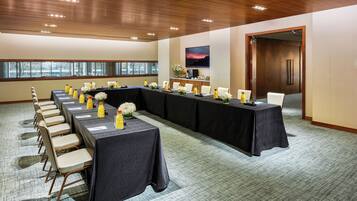 Un salón de conferencias con una larga mesa, sillas y una pantalla de televisión.