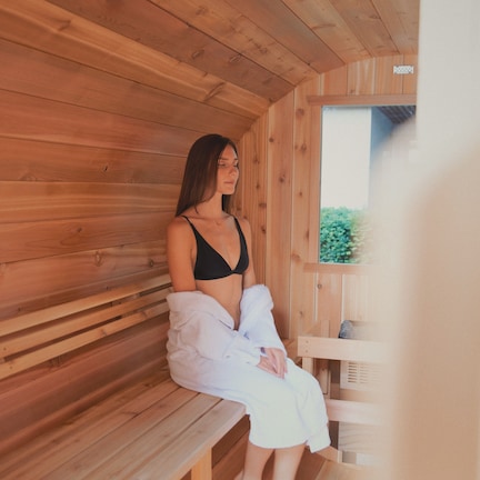 A wooden sauna with benches and a bench with a person sitting on it.