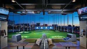 A golf simulation room with a city view, multiple screens, and a seating area. - The SKYLOFTS at MGM Grand (Las Vegas)