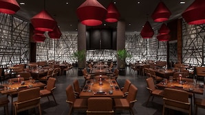 A spacious restaurant with multiple dining tables, red pendant lights, and a modern geometric wall design. - The SKYLOFTS at MGM Grand (Las Vegas)