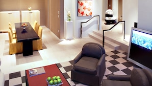 A modern hotel lobby with a dining area, seating, a staircase, and a TV screen. - The SKYLOFTS at MGM Grand (Las Vegas)