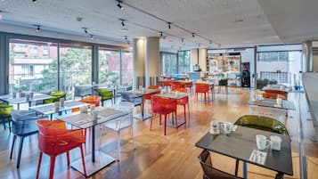Um café moderno com mesas, cadeiras, janelas amplas e um balcão de pastelaria.