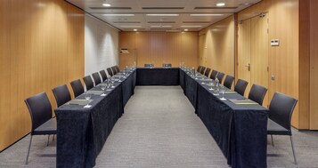 A conference room with a long table, chairs, and water glasses.