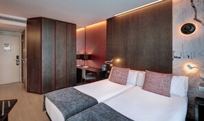 A modern hotel room with a large bed, a desk, a wardrobe, and a wall-mounted light fixture. - Sercotel Rosellon (Barcelona)