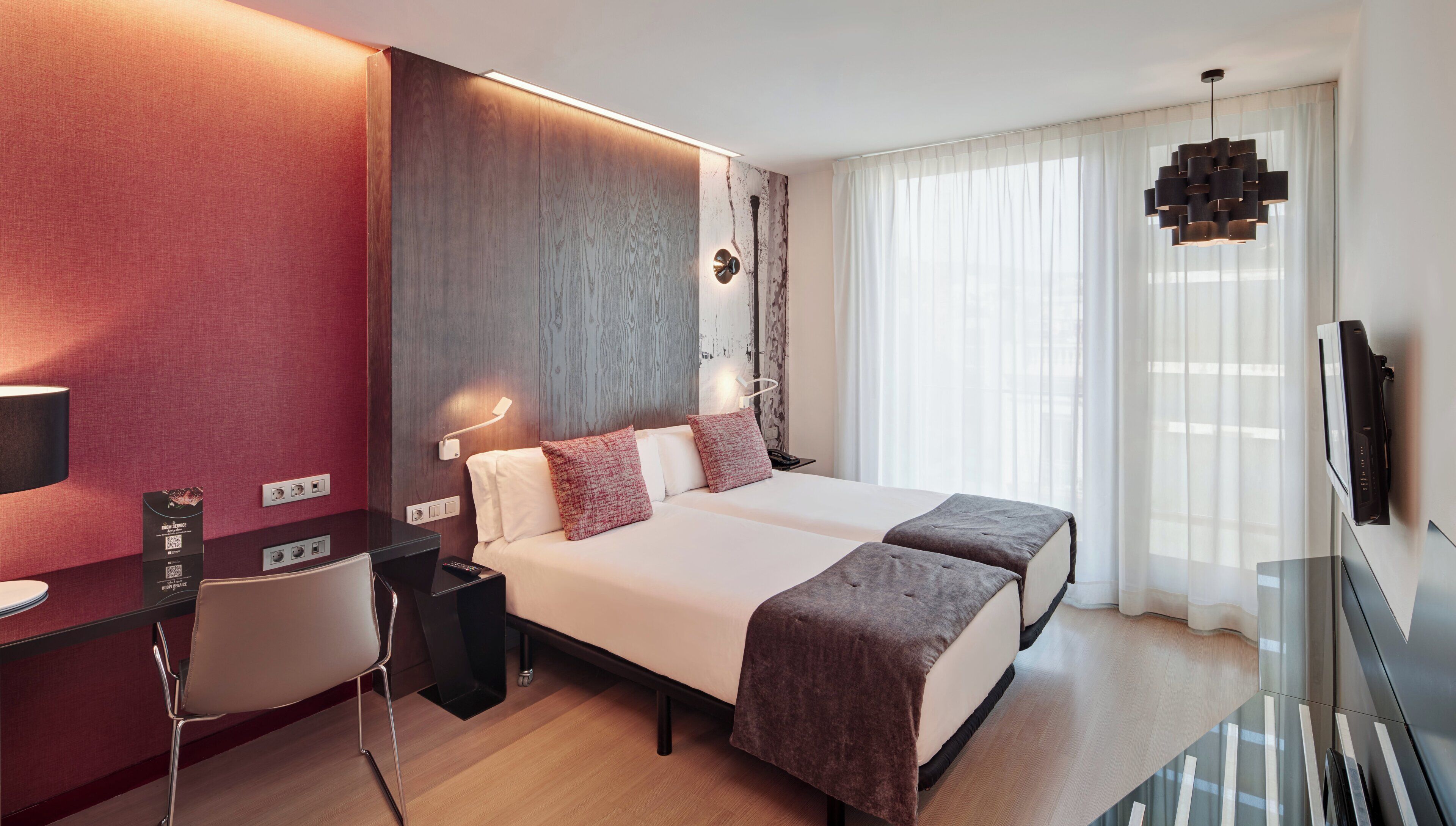 Une chambre d’hôtel moderne, dotée d’un grand lit, de tables de chevet, d’un bureau et d’une télévision.