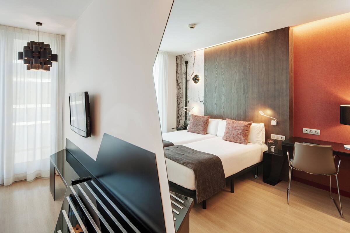 Une chambre d’hôtel moderne équipée d’un lit, de tables de chevet, d’un bureau et d’une chaise.
