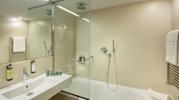 A modern bathroom with a glass-enclosed shower, a white sink with toiletries, and a large mirror.
