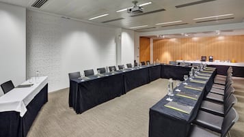 Un salón de conferencias con una mesa larga, sillas y un revestimiento de madera.