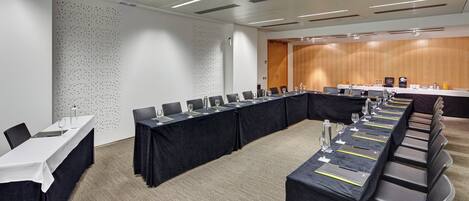 A conference room with a long table, chairs, and a wooden panel wall.