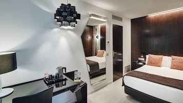 Una habitación de hotel con cama, mesita de noche, lámpara y espejo.