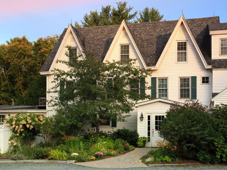 A two-story house with a symmetrical facade, a central entrance, and a well-maintained garden with various plants and flowers.