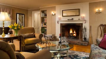 A cozy living room with a fireplace, a chess table, and a comfortable sofa.