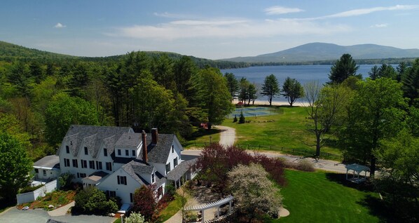 A large white house with a well-maintained lawn and a view of a lake.