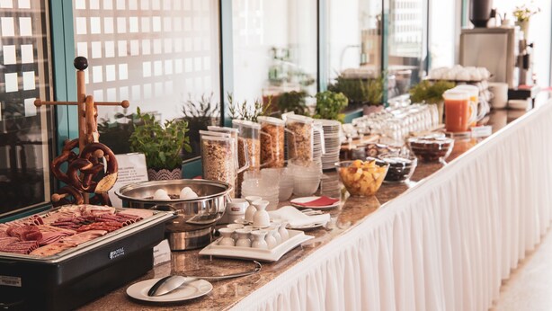 A buffet setup with various food items and condiments. - Hotel Le Village (Winnenden)